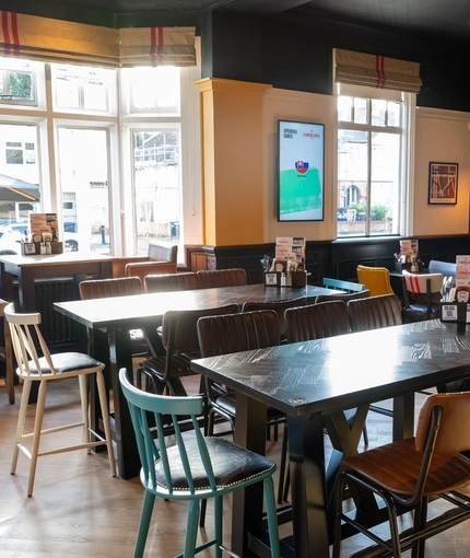 An interior restaurant seating area at Whitehills, with TVs on the walls.