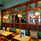 The interior restaurant seating area of The Fountains Abbey, with upholstered booth seating, wooden tables, a fireplace, and a wood panelled wall inlaid with mirrors.