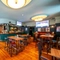 The bar and interior restaurant seating area at the Royal George in Euston; with wooden flooring, an upholstered booth seat, TVs on the walls, and gaming machines.