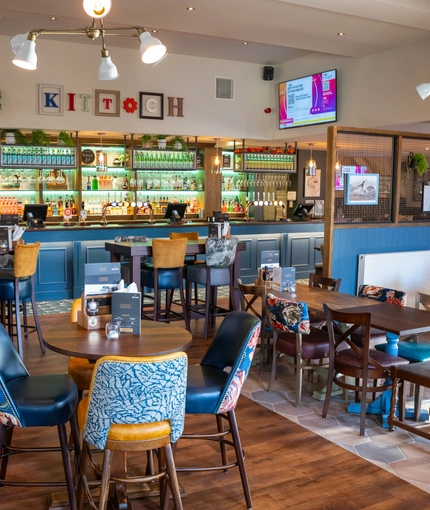 The bar and interior restaurant seating area at The Kittoch, with a TV on the wall.
