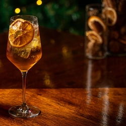Two cocktail type drinks on a bar.  One in a low ball tumbler and the other is in a stemmed glass.