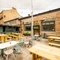 The exterior beer garden and seating area with benches and tables and chairs and also two TV's on the walls at the Armstrongs.
