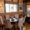 The interior restaurant seating area at The Hollybush in Lichfield, with upholstered chairs, bottles of wine in a glass fronted cabinet, a lamp on the windowsill, and a large potted plant.