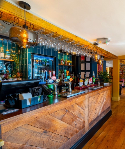 The wood panelled bar and interior restaurant seating area of The Windmill Inn in York, with a TV on the wall and a fireplace.