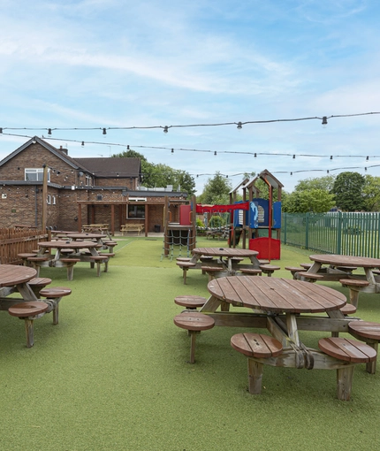 Exterior play area and beer garden of a pub with a seating area.