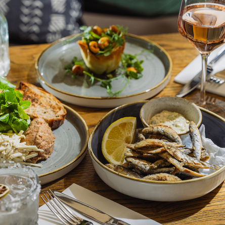An advertising image showing a selection of starter dishes from the Prix Fixe menu sat on a table within the interior restaurant seating area at The Four Oaks.
