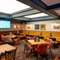 An interior restaurant seating area at the Old School House in Aberdeen, with upholstered chairs and booth seating, wood panelling and a TV on the wall, and large, square sky lights in the ceiling.