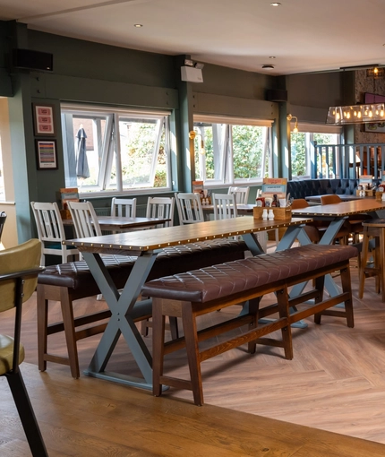 The interior restaurant seating area at The Man On The Moon, with upholstered seating, wooden tables, and TVs on the walls.