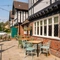 The exterior facade and seating area at The Walkford, with flower baskets hanging on the walls, and string lights above the tables and chairs.