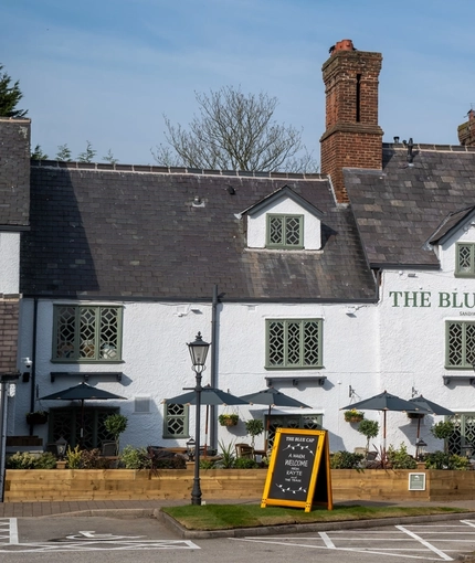 The exterior facade, signage, and seating area of The Blue Cap in Sandiway.