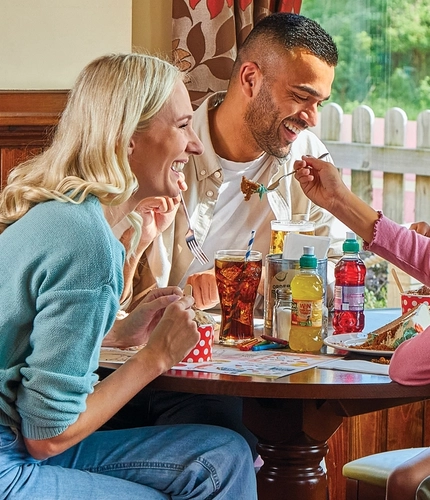 family sitting round a table in a restaurant eating cake and ice cream