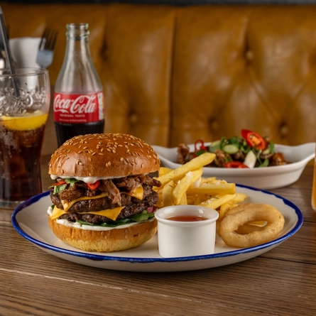 A plated Crispy Duck Burger on a wooden table.