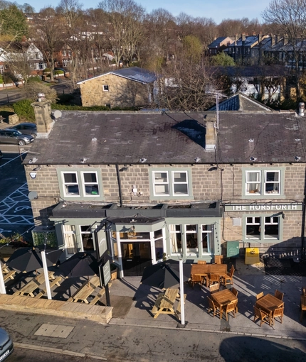 An aerial view of the exterior facade, signage, and seating area of The Horsforth, with a view of the surrounding streets.