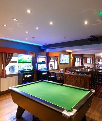 interior dining area of a pub with a pool table and a few gambling machines