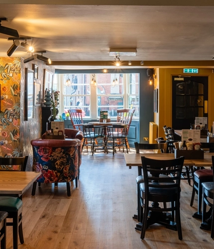 The interior restaurant seating area at The Windmill Inn, with wooden flooring and a fireplace.