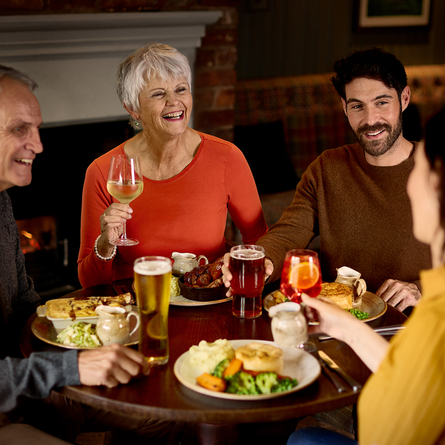 An image of 4 customers enjoying mains dishes and various drinks within the interior restaurant and seating area at a Chef & Brewer venue.