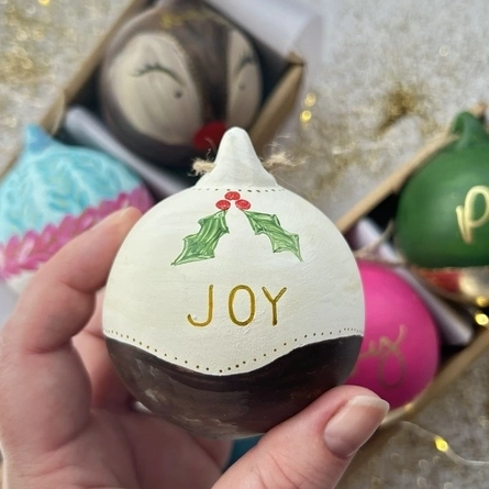 An image of a person holding a Christmas Bauble advertising a Bauble Painting Workshop What's On event at The Cart & Horses.