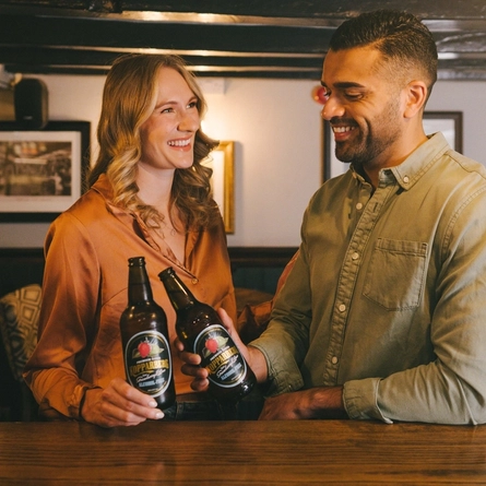 Two friends stood at the bar drinking alcohol free Kopparberg in a Greene King venue.