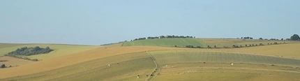 An image of rolling hills and fields with buildings in the distance.