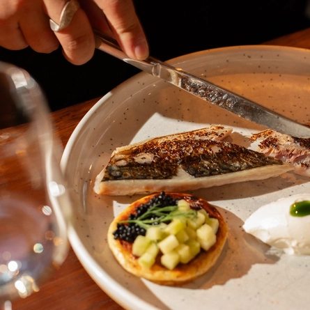 An image of a customer cutting into a plated dish within the interior restaurant and seating area at The Ubiquitous Chip.