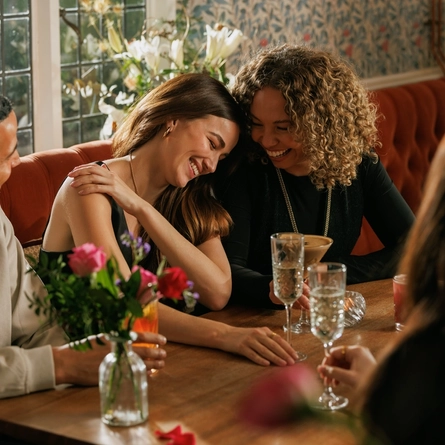 An image focusing on 3 customers sat with friends enjoying Valentines Day Drinks sat at a table within the interior seating area of The Crown.