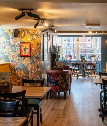 The interior restaurant seating area at The Windmill Inn, with wooden flooring and a fireplace.