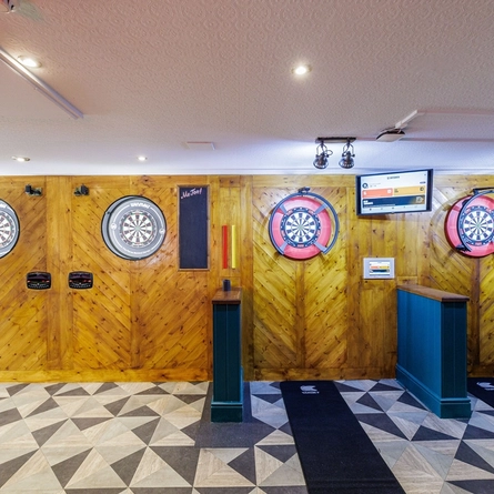 The interior games area with dartboard lanes and TV screens at The Clive Arms.