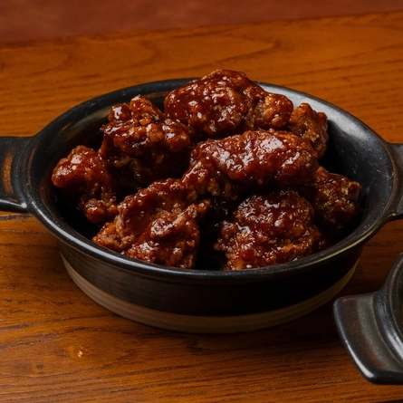 A close up view of Karage Chicken Wings and Cauliflower Wings served in small roasting dishes which sit on a wooden restaurant table along with a glass of Level Head.