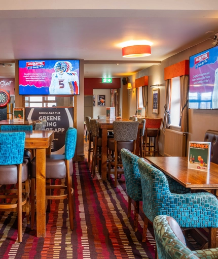 The interior restaurant seating area of The Royal Horse, with TVs on the walls and a dartboard.