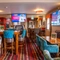 The interior restaurant seating area of The Royal Horse, with TVs on the walls and a dartboard.