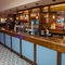 The interior bar with hanging pendant lighting, venue branding on a mirror behind the bar and tiled flooring at The Castle View.