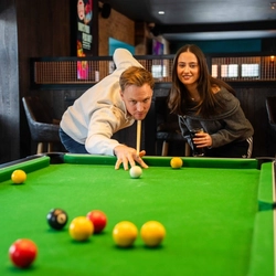 An image showing 2 people enjoying a game of pool within the interior of a Flaming Grill venue.