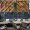 An exterior beer garden seating area at The Royal Oak, with wicker chairs and bench seating underneath a wooden pergola decorated with artificial flowers.