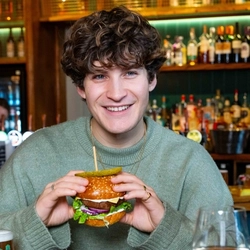 A group of friends sat in the interior restaurant and seating area in a Urban Social venue, enjoying meals off the lunch menu and drinks, the focus is one one male from the group.