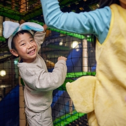 A child smiling at the camera in an indoor play area.