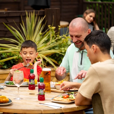 A family seated at an outdoor table in a beer garden, enjoying a meal.