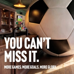 A banner promoting the new football season at Community Social venues. The banner shows an interior of a Community Social-branded sports bar featuring a giant football-shaped wall installation beside the bar. Large white text reads “YOU CAN’T MISS IT.” with smaller text underneath stating “MORE GAMES. MORE GOALS. MORE GLORY.” A television screen showing a football match is visible in the background above beer taps and shelves of bottles.