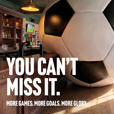 A banner promoting the new football season at Community Social venues. The banner shows an interior of a Community Social-branded sports bar featuring a giant football-shaped wall installation beside the bar. Large white text reads “YOU CAN’T MISS IT.” with smaller text underneath stating “MORE GAMES. MORE GOALS. MORE GLORY.” A television screen showing a football match is visible in the background above beer taps and shelves of bottles.
