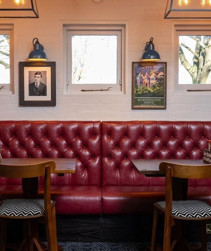 An interior restaurant seating area at the Clocktower, with upholstered booth seating, and framed artwork on the walls.