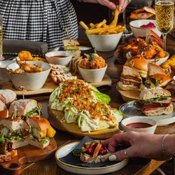 A variety of grazing board sharer dishes being enjoyed by people within the exterior beer garden seating area at a Crafted venue.