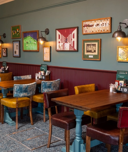 An interior restaurant seating area at the Golden Hind, with upholstered chairs, and framed artwork on the wall.