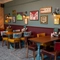 An interior restaurant seating area at the Golden Hind, with upholstered chairs, and framed artwork on the wall.