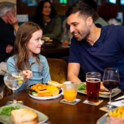 An image of a family enjoying various dishes and drinks within the interior restaurant seating area at a Community Pubs With Food venue.