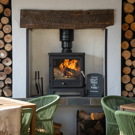 An interior seating area at The Blue Cap, with wicker style chairs, and a log burning fireplace.