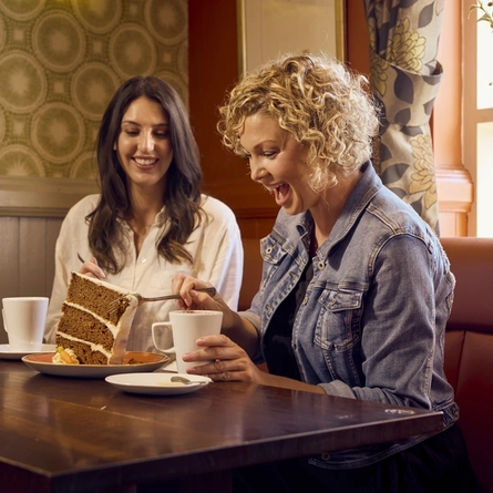 Two people enjoying coffee & cake at a Farmhouse Inn venue.