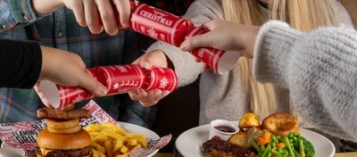 An interior shot of people celebrating Christmas and enjoying festive food in the restaurant/seating area at a Flaming Grill venue.