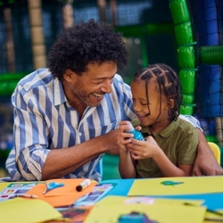 An image of a child and a man participating in crafts at a Wacky Warehouse.