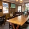 An interior restaurant seating area at The Woolpack Inn; with wooden flooring, an upholstered booth seat against the windows, and a large TV on the wall.