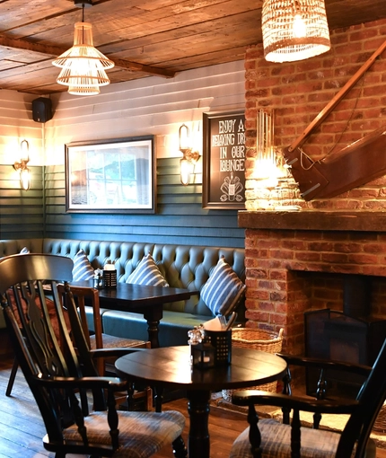 Interior dining area of a pub with a fireplace.
