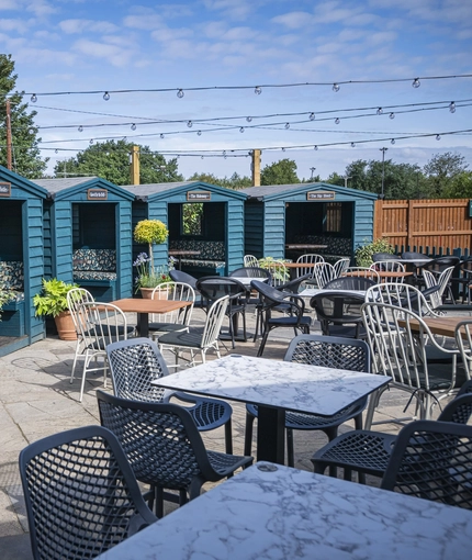 The exterior beer garden seating area and covered seating huts at The Bells.